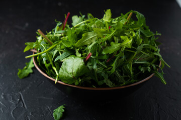 Mix salad greens. Arugula, lettuce, spinach in black bowl