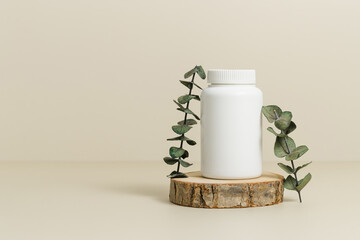 Medicine bottle for vitamins or pills on wooden podium with eucalyptus leaves, natural supplement,...