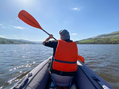 Rear view of woman kayaking on lake on sunny day
