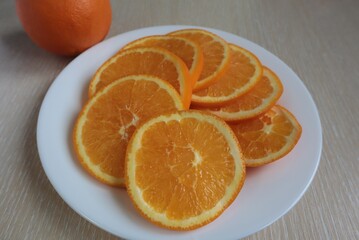 Naklejka na ściany i meble Cut the orange into circles on a white plate on the table.