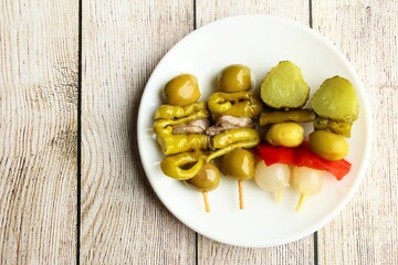 pickled skewers of mixed vegetables and anchovy fish. stock photo on clear wooden background top view copy space 