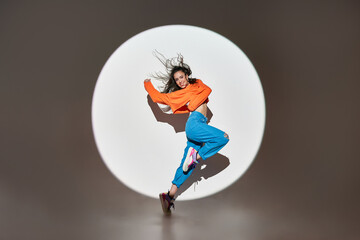 Happy woman dancing with raised hands in studio