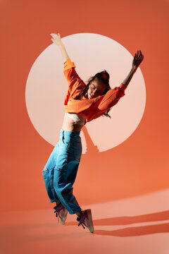 Happy woman dancing with raised hands in studio