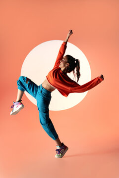 Happy woman dancing with raised hands in studio