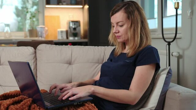 Freelancer woman lying on sofa and use laptop for working. Home workplace, remote work