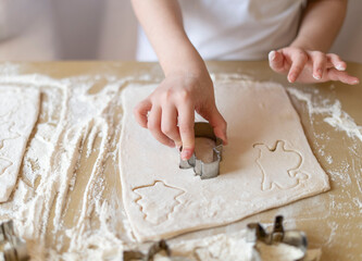Children's hands press the mold on the dough, making cookies
