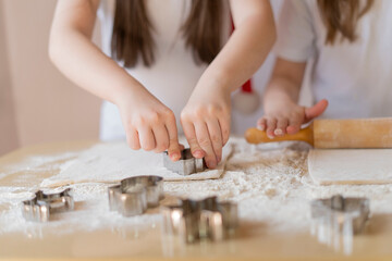 Fototapeta na wymiar Children's hands press the mold on the dough, making cookies