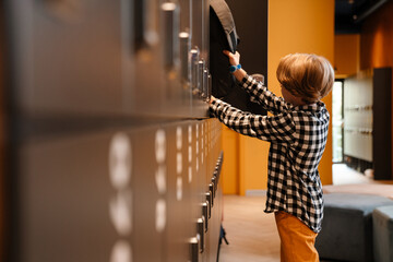 White boy putting his backpack in checkroom at school