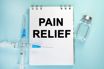 Notepad with pain relief inscription on it. Ampoule and syringe.