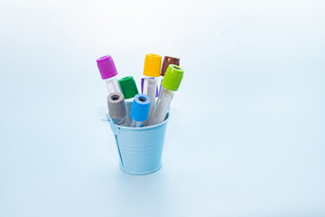 Two vacuum tubes for collection and blood samples in bucket on blue background for laboratory