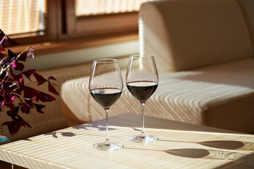 Two glasses of red wine indoors in sunlight from the window
