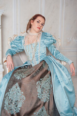 Beautiful young woman in medieval style blue dress in the armchair.