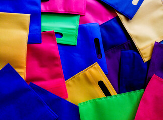 collection of colorful tote bags. made of polypropylene. stack of non-woven bags with perforated...