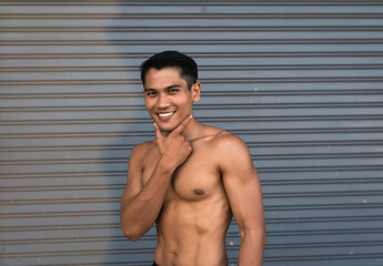 Obraz premium Young man with fit and firm muscle,raise finger touch chin,happy feeling,