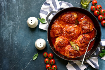 Chicken thighs stewed in tomato sauce. Top view with copy space.