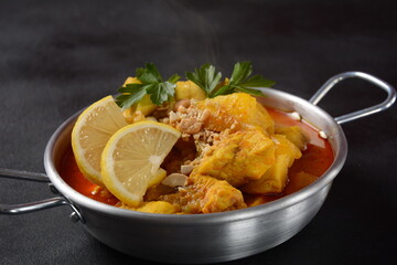 A Chicken Massaman Curry in black bowl at dark background. Massaman Curry is Thai Indian best dish with chicken meat, potato, onion and many spices is influenced by Malay and Thai Muslim cultures.