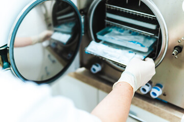 Dental instruments are sterilized in the sterilizing oven by the dentist's assistant.