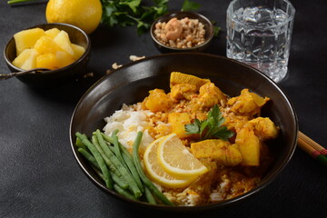 A Chicken Massaman Curry in black bowl at dark background. Massaman Curry is Thai Indian best dish with chicken meat, potato, onion and many spices is influenced by Malay and Thai Muslim cultures.