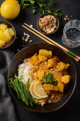 A Chicken Massaman Curry in black bowl at dark background. Massaman Curry is Thai Indian best dish with chicken meat, potato, onion and many spices is influenced by Malay and Thai Muslim cultures.