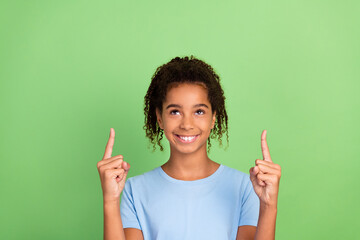 Portrait of attractive cheerful girl demonstrating up copy place ad look idea isolated over green pastel color background