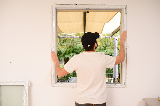 handsome young professional man installing and replacing a new home window in client house for improvement energy saving efficiency isolation