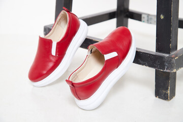 Red beautiful fashionable female loafers shoes. Studio shoot on white background for a magazine,...