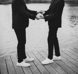 European Gay Couple holding hands, wearing black suits, wedding day of a same sex couple. Black and white art photography.