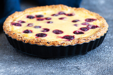 Homemade ricotta cheese pie with cherries on a gray background. Close up. Hearty baking.