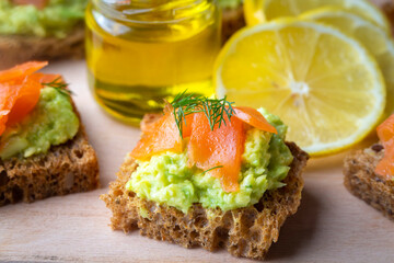 Toasts with avocado and smoked salmon on the wooden plate