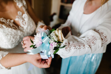 Hand-decorating boutonniere of flowers and ribbons. Bride putting bridesmaid on hand Buttonhole....
