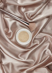 Fototapeta premium Face powder and brush,on a beige silk pastel background,make up,flat layot