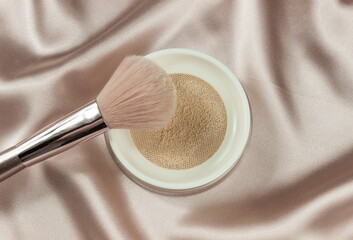 Face powder and brush,on a beige silk pastel background,make up,flat layot
