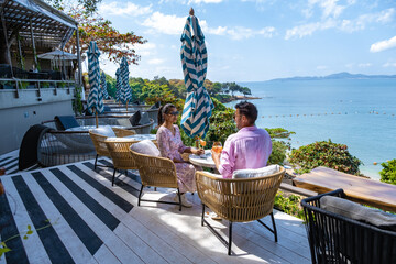 couple having lunch at a restaurant looking out over the ocean of Pattaya Thailand, man and woman...