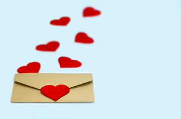 A kraft envelope with red hearts on a light blue background. The concept of Valentine's day, love, anniversary. copy space