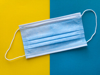 Top view of a new surgical mask on a juicy colorful yellow and blue paper background.