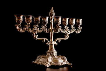 Hanukkah lamp (Hanukkah menorah), made of metal, close-up, on a black background.