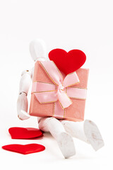 Valentines Day background. A gift box with a wooden mannequin on a white background. Flat lay. Vertical photo