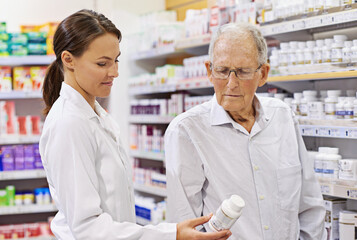 Fototapeta na wymiar Sharing her wealth of knowledge. Shot of a young pharmacist helping an elderly customer.