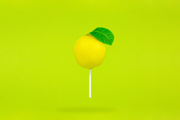 Lemon in form lollipop with stick on light green background. Single Lollipop