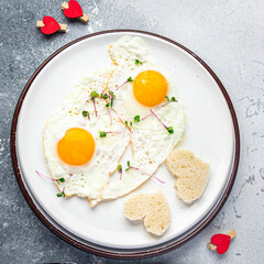 Valentine's day egg breakfast on the table scrambled fried eggs heart shape love holiday decoration date copy space food background