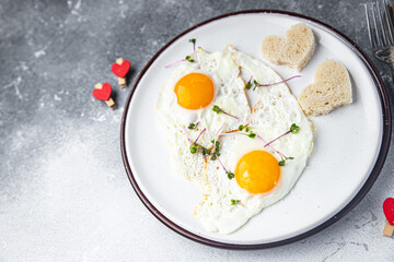 Valentine's day egg breakfast on the table scrambled fried eggs heart shape love holiday decoration date copy space food background