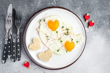 Valentine's day egg breakfast on the table scrambled fried eggs heart shape love holiday decoration date copy space food background