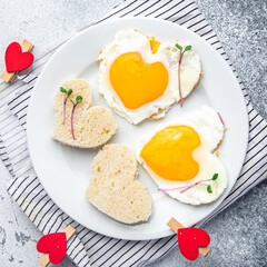 Valentine's day egg breakfast on the table scrambled fried eggs heart shape love holiday decoration date copy space food background