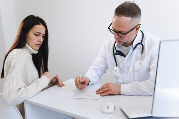 Doctor writes a prescription for medicines to his patient. Woman at the medical appointment