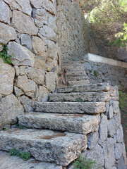 Close up of stone stairway in rock. Ancient stone steps in the rock. Stone wall with rustic stairs. Nature, paths and trails.