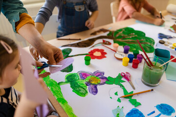 Close-up of little kids working on project with teacher during creative art and craft class at...