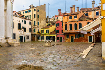 Cobblestoned square surrounded by old colorful houses in Venice, Italy.