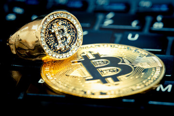 Ring with bitcoin symbol on keyboard keys and representative bitcoin coin. There are imitation diamonds on the ring, the symbol of wealth. Ring with bitcoin symbol in selective focus.