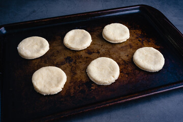 Overhead View of Uncooked Biscuits on a Sheet Pan: Raw cut out biscuit dough on a metal baking pan