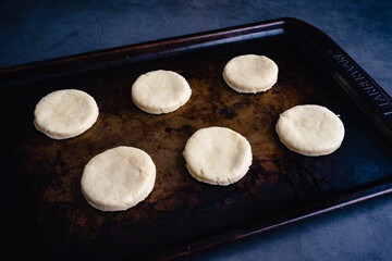 Overhead View of Uncooked Biscuits on a Sheet Pan: Raw cut out biscuit dough on a metal baking pan